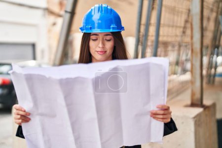 Photo for Young beautiful hispanic woman architect looking house plans at street - Royalty Free Image
