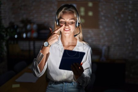 Photo for Young blonde woman working at the office at night pointing with hand finger to face and nose, smiling cheerful. beauty concept - Royalty Free Image