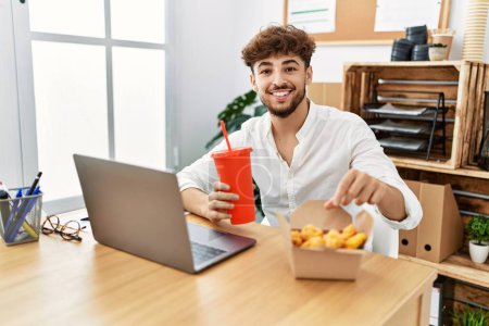 Photo for Young arab man using laptop having lunch at office - Royalty Free Image