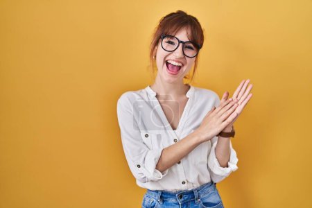 Téléchargez les photos : Young beautiful woman wearing casual shirt over yellow background clapping and applauding happy and joyful, smiling proud hands together - en image libre de droit