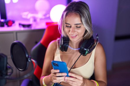 Téléchargez les photos : Jeune femme blonde streamer en utilisant ordinateur et smartphone à la salle de jeux - en image libre de droit
