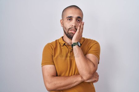 Foto de Hispanic man with beard standing over white background thinking looking tired and bored with depression problems with crossed arms. - Imagen libre de derechos