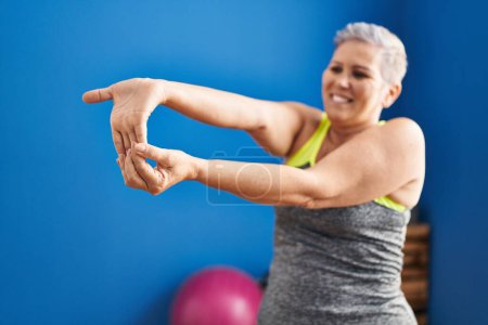 Téléchargez les photos : Middle age woman smiling confident stretching at sport center - en image libre de droit