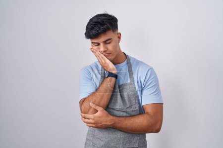 Photo for Hispanic young man wearing apron over white background thinking looking tired and bored with depression problems with crossed arms. - Royalty Free Image