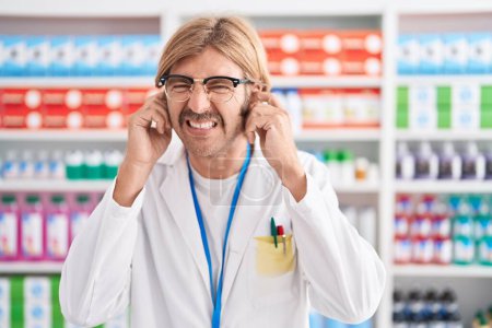 Photo for Caucasian man with mustache working at pharmacy drugstore covering ears with fingers with annoyed expression for the noise of loud music. deaf concept. - Royalty Free Image