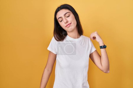 Téléchargez les photos : Young beautiful woman standing over yellow background stretching back, tired and relaxed, sleepy and yawning for early morning - en image libre de droit