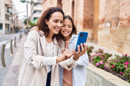 Photo for Woman and girl mother and daughter having video call at street - Royalty Free Image