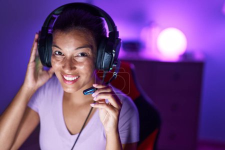 Téléchargez les photos : Young beautiful hispanic woman streamer playing video game using computer at gaming room - en image libre de droit