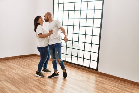 Photo for Young hispanic couple smiling happy dancing at empty new home. - Royalty Free Image