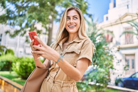 Photo for Young blonde girl smiling happy using smartphone at the city. - Royalty Free Image
