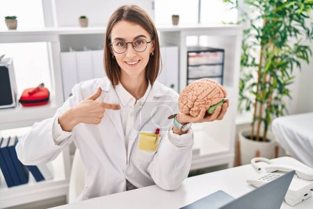 Photo for Young caucasian doctor woman holding brain as mental health concept pointing finger to one self smiling happy and proud - Royalty Free Image
