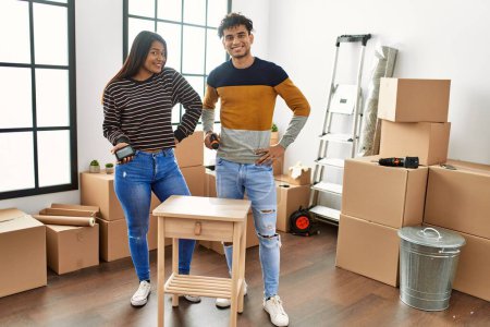 Young latin couple smiling happy assembling piece of furniture at new home.