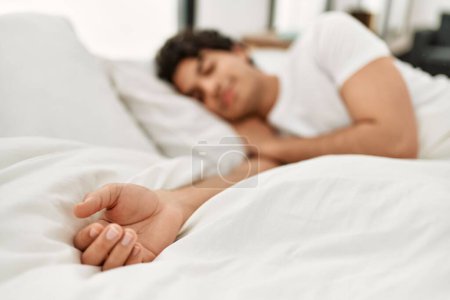 Téléchargez les photos : Jeune homme hispanique dormant allongé sur le lit dans la chambre. - en image libre de droit