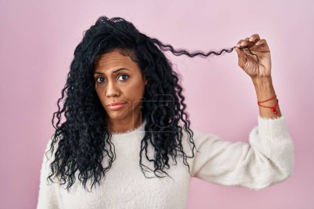 Photo for Middle age hispanic woman holding curly hair skeptic and nervous, frowning upset because of problem. negative person. - Royalty Free Image