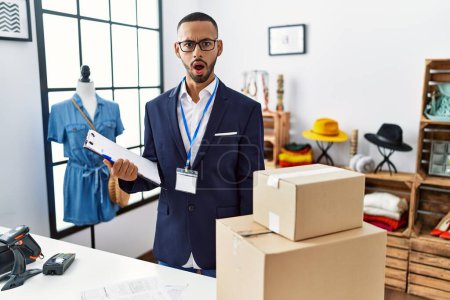 Photo for African american man working as manager at retail boutique in shock face, looking skeptical and sarcastic, surprised with open mouth - Royalty Free Image