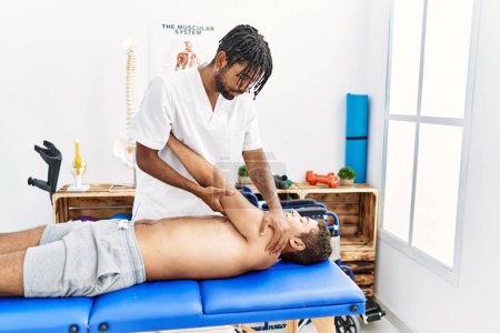 Téléchargez les photos : Deux hommes physiothérapeute et patient ayant séance de réadaptation étirant le bras à la clinique - en image libre de droit