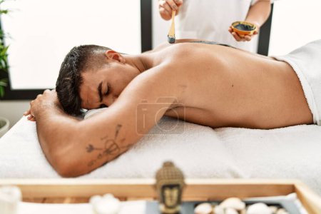 Foto de Hombre hispano joven relajado teniendo tratamiento de la piel en el centro de belleza - Imagen libre de derechos
