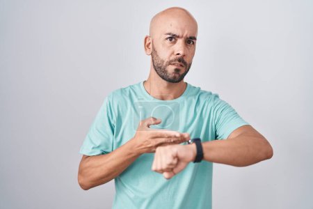Téléchargez les photos : Middle age bald man standing over white background in hurry pointing to watch time, impatience, upset and angry for deadline delay - en image libre de droit