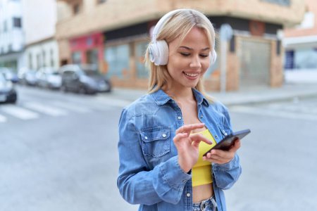 Photo for Young blonde woman smiling confident listening to music at street - Royalty Free Image