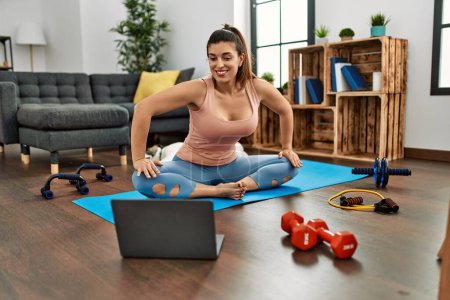 Photo for Young woman smiling confident having online stretching class at home - Royalty Free Image