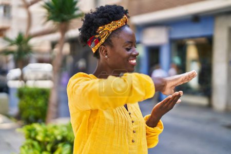 Foto de Joven mujer afroamericana haciendo gastar dinero símbolo con las manos en la calle - Imagen libre de derechos