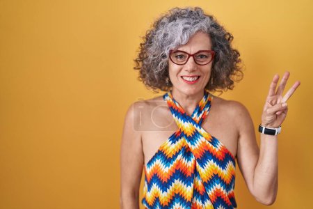 Photo for Middle age woman with grey hair standing over yellow background showing and pointing up with fingers number three while smiling confident and happy. - Royalty Free Image