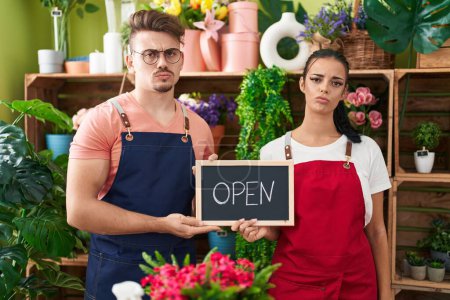 Photo for Young hispanic man a woman working at florist holding open sign depressed and worry for distress, crying angry and afraid. sad expression. - Royalty Free Image
