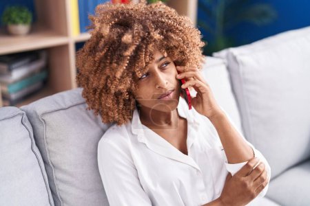 Téléchargez les photos : African american woman talking on the smartphone with serious expression at home - en image libre de droit
