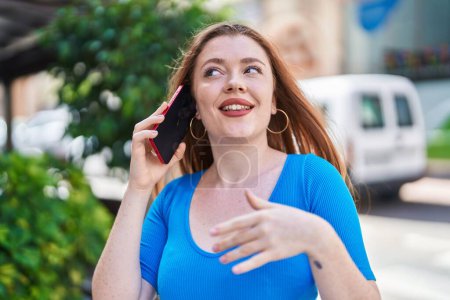 Foto de Mujer pelirroja joven sonriendo confiado hablando en el teléfono inteligente en la calle - Imagen libre de derechos