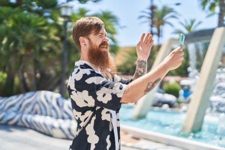 Téléchargez les photos : Jeune rousse homme souriant confiant ayant appel vidéo au parc - en image libre de droit