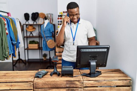 Photo for Young african man working as shop assistance speaking on the phone at retail shop - Royalty Free Image