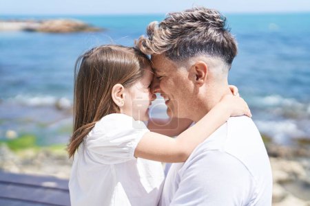 Téléchargez les photos : Père et fille souriant confiants s'embrassant au bord de la mer - en image libre de droit