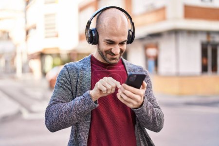 Téléchargez les photos : Jeune homme souriant confiant écoutant de la musique dans la rue - en image libre de droit