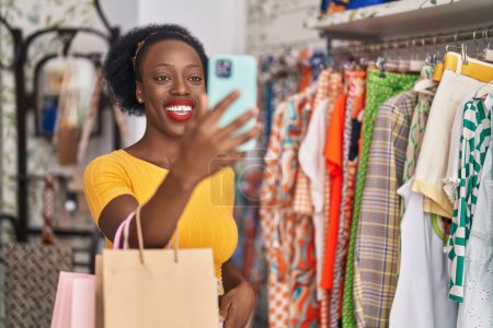 Foto de African american woman customer holding shopping bags having video call at clothing store - Imagen libre de derechos