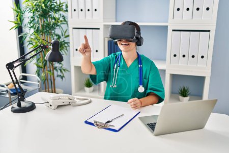 Photo for Young beautiful hispanic woman doctor using virtual reality glasses at clinic - Royalty Free Image