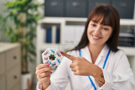 Photo for Young beautiful hispanic woman doctor holding pills organizer box at clinic - Royalty Free Image