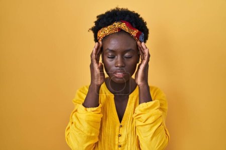 Photo for African young woman wearing african turban with hand on head for pain in head because stress. suffering migraine. - Royalty Free Image