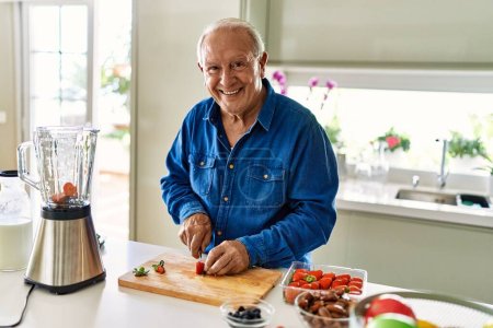 Photo for Senior man smiling confident cutting strawberry at kitchen - Royalty Free Image