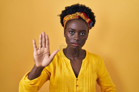 Photo for African young woman wearing african turban doing stop sing with palm of the hand. warning expression with negative and serious gesture on the face. - Royalty Free Image