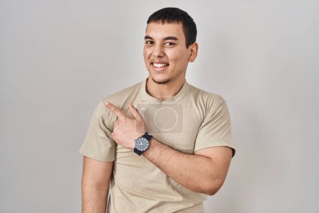 Téléchargez les photos : Young arab man wearing casual t shirt cheerful with a smile on face pointing with hand and finger up to the side with happy and natural expression - en image libre de droit