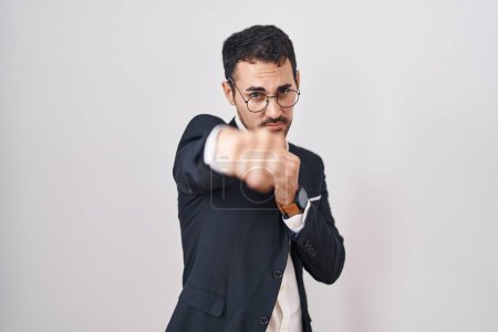 Foto de Handsome business hispanic man standing over white background punching fist to fight, aggressive and angry attack, threat and violence - Imagen libre de derechos
