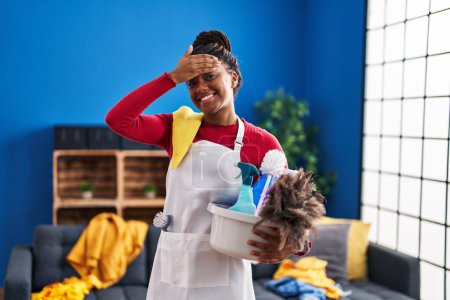 Photo for Young african american with braids cleaning the house holding cleaning products stressed and frustrated with hand on head, surprised and angry face - Royalty Free Image