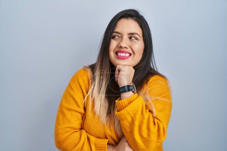 Photo for Young hispanic woman standing over isolated background thinking worried about a question, concerned and nervous with hand on chin - Royalty Free Image