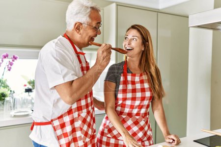 Photo for Middle age hispanic couple smiling happy cooking and tasty meal at the kitchen. - Royalty Free Image