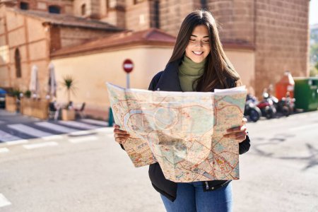 Téléchargez les photos : Jeune belle femme hispanique souriant confiant tenant la carte de la ville à la rue - en image libre de droit