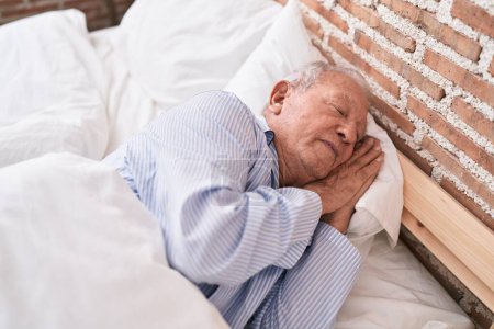 Hombre de pelo gris de mediana edad acostado en la cama durmiendo en el dormitorio