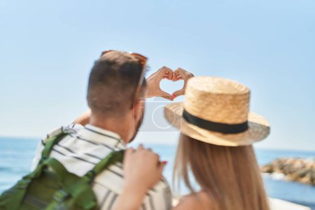 Téléchargez les photos : Homme et femme touriste couple faisant geste de coeur à la mer - en image libre de droit