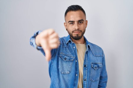 Photo for Young hispanic man standing over isolated background looking unhappy and angry showing rejection and negative with thumbs down gesture. bad expression. - Royalty Free Image