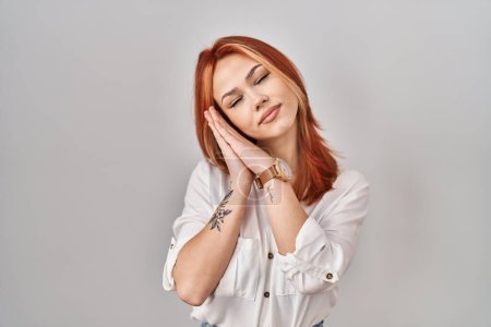 Photo for Young caucasian woman standing over isolated background sleeping tired dreaming and posing with hands together while smiling with closed eyes. - Royalty Free Image
