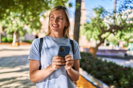 Photo for Young blonde woman smiling confident using smartphone at park - Royalty Free Image